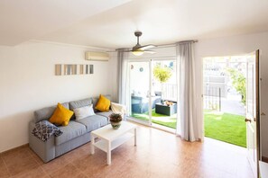 A living room with a grey sofa, a white coffee table, and a ceiling fan.