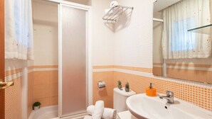 A bathroom with a shower, toilet, sink, and a mirror. - Golden Coast Retreat by Fidalsa (Creixell)