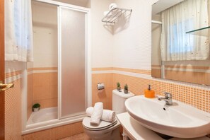 Une salle de bain équipée d’une douche, de toilettes, d’un lavabo et d’un miroir.