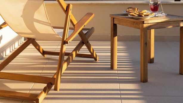 A wooden deck with a wooden chair and a small table, a glass of red drink, and a plate of food. - Atman Eco Lodge (Souli)