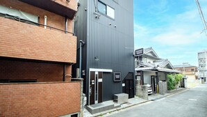 A modern building with a dark facade, a visible entrance, and a sign indicating it is an apartment building. - Apartment Sanjo (Nara)
