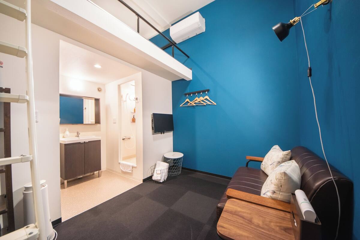 A room with a blue wall, a wooden sofa, a TV, and a ceiling-mounted lamp.