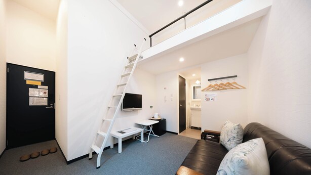 A modern room with a staircase, a flat-screen TV, a sofa, and a small table. - Apartment Sanjo (Nara)