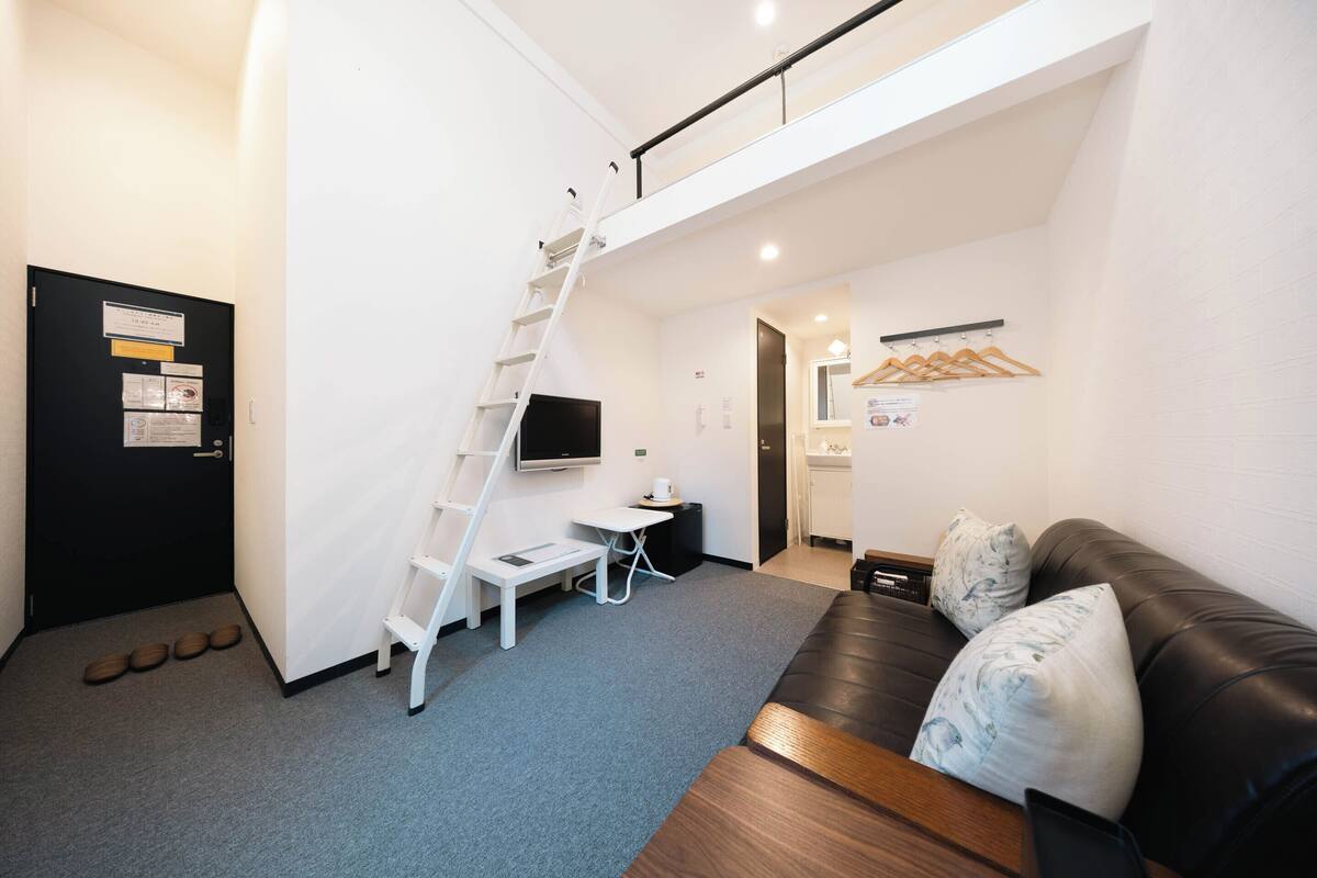 A modern room with a staircase, a flat-screen TV, a sofa, and a small table.