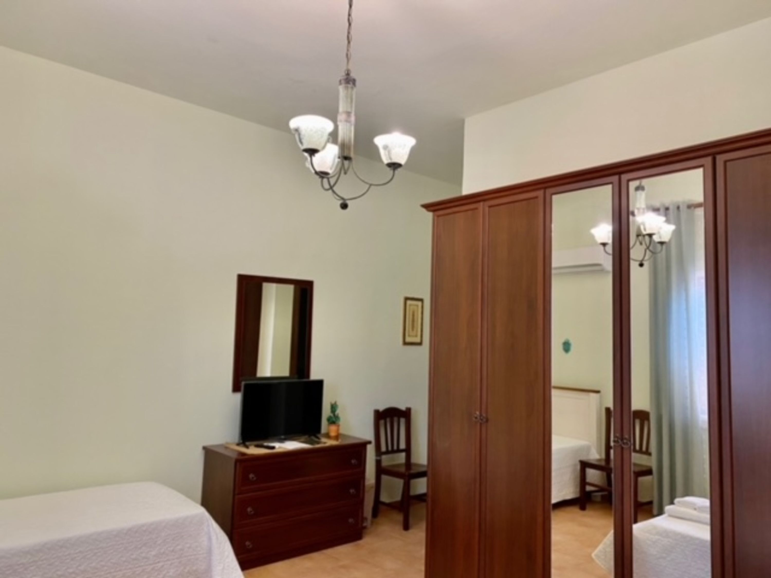 Ein Schlafzimmer mit Bett, Schminktisch, Kleiderschrank und einer Chandelier.