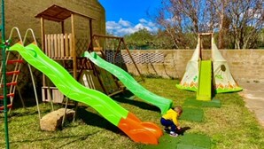 A playground with two slides and a climbing structure.