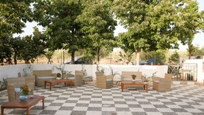 An outdoor seating area with checkered flooring, wicker furniture, and potted plants.