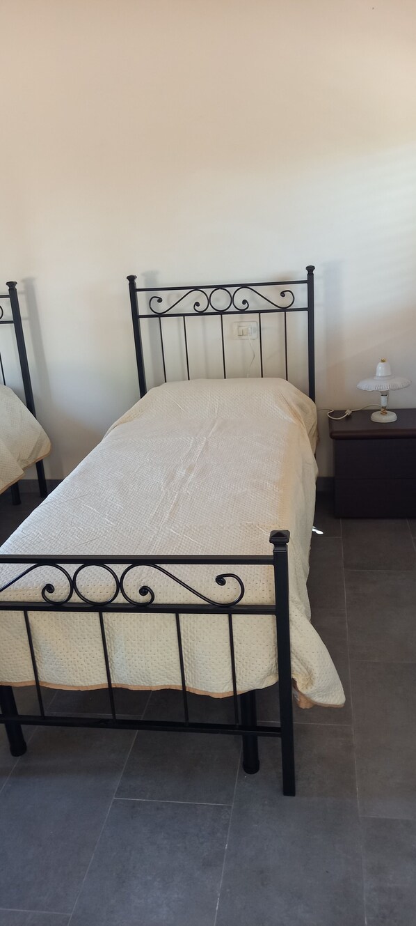 A single bed with a metal frame and a textured white mattress.