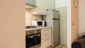 A compact kitchen with a gas stove, microwave, oven, and a refrigerator. - Casa di Ziva in Rome (Rome)