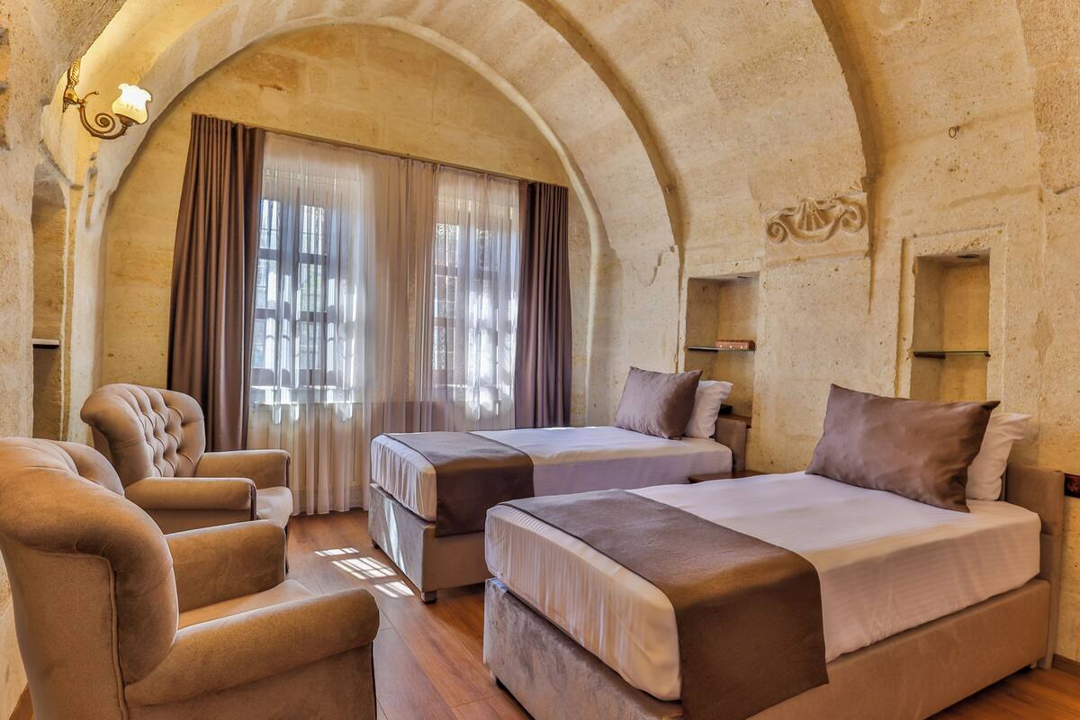 Quarto de hotel com duas camas, um sofá e um candelabro.