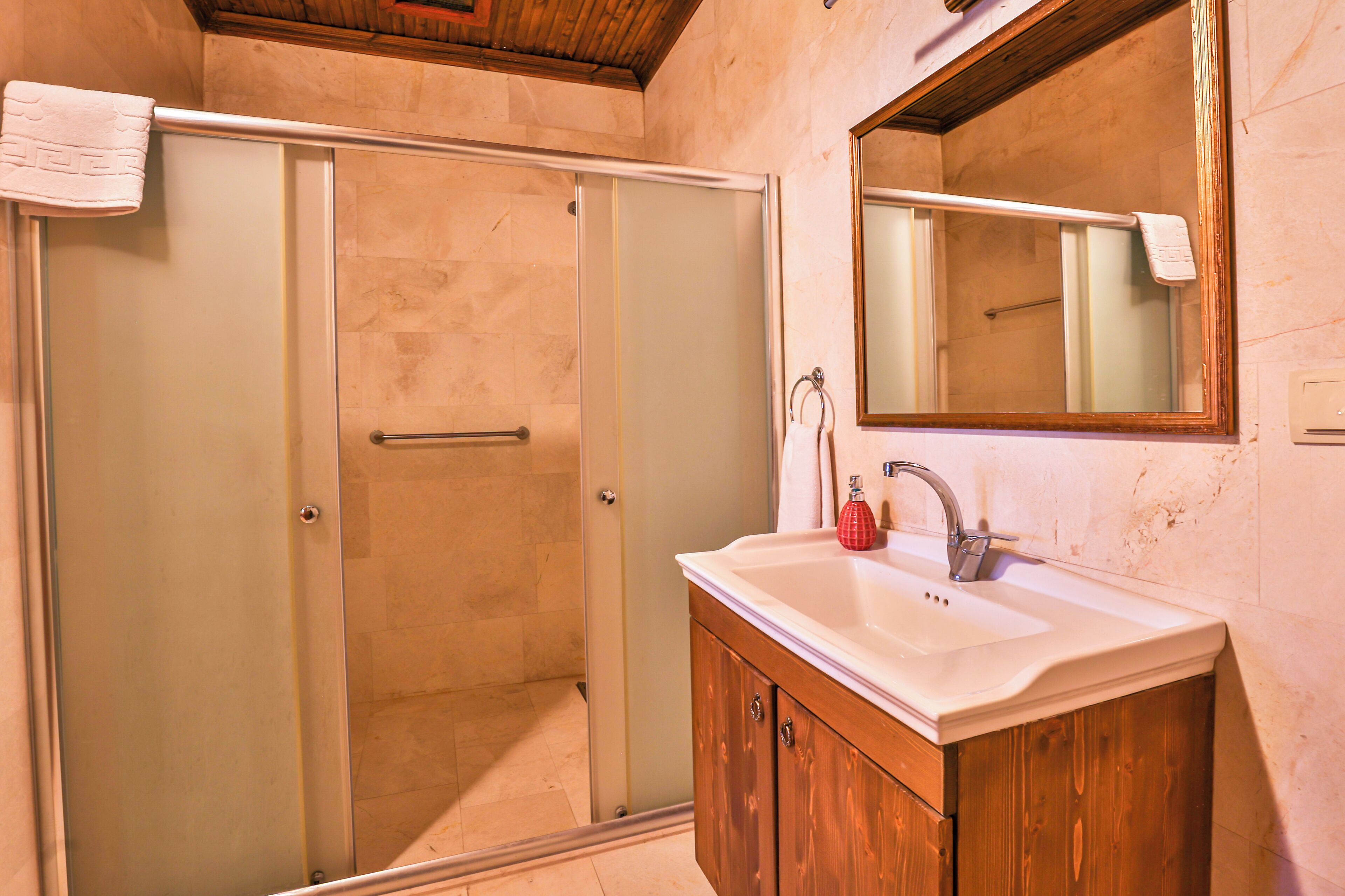 Une salle de bain avec une douche à parois de verre, un meuble-lavabo en bois et un miroir au-dessus du meuble-lavabo.