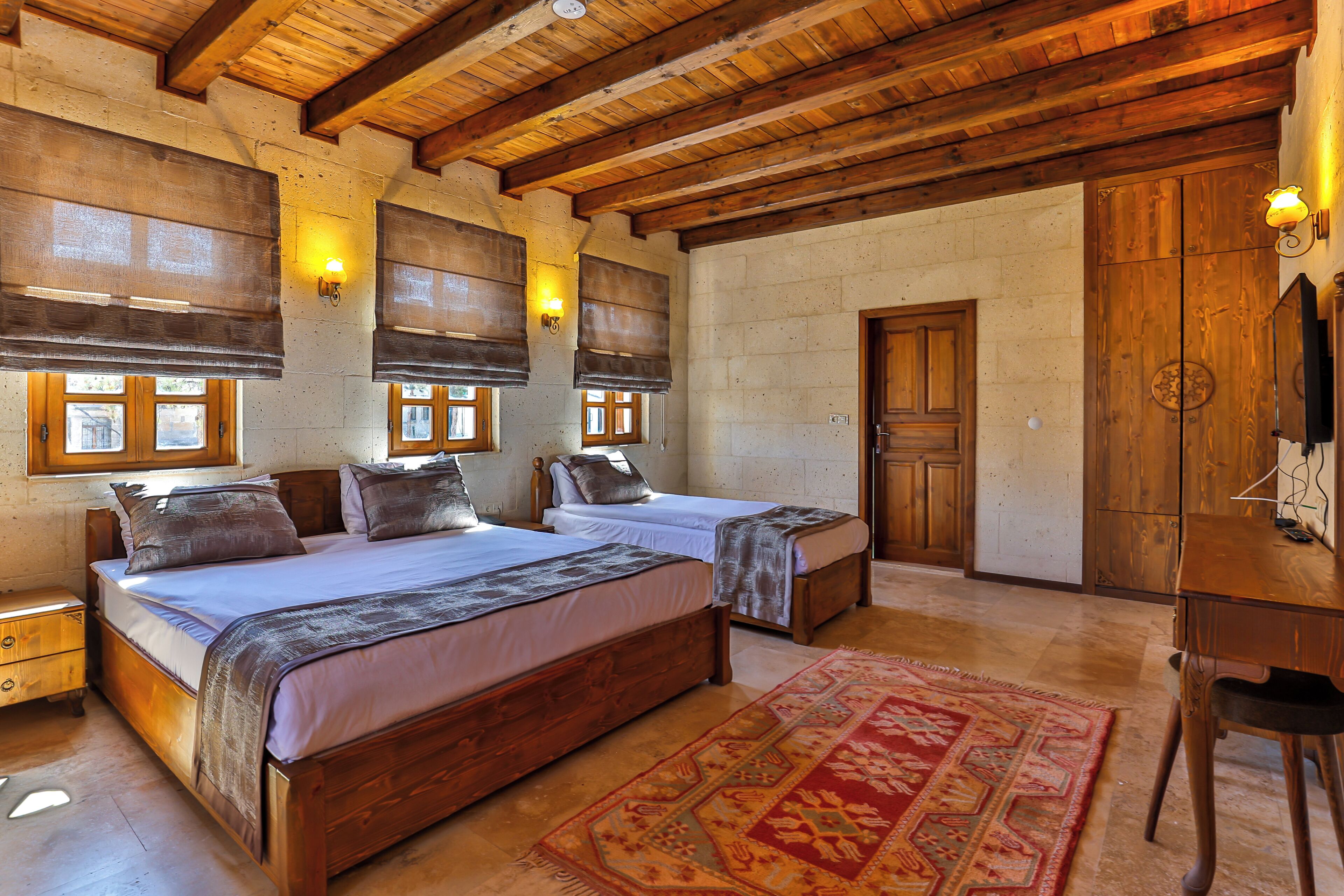 A room with two wooden beds, a wooden desk, and a large rug.