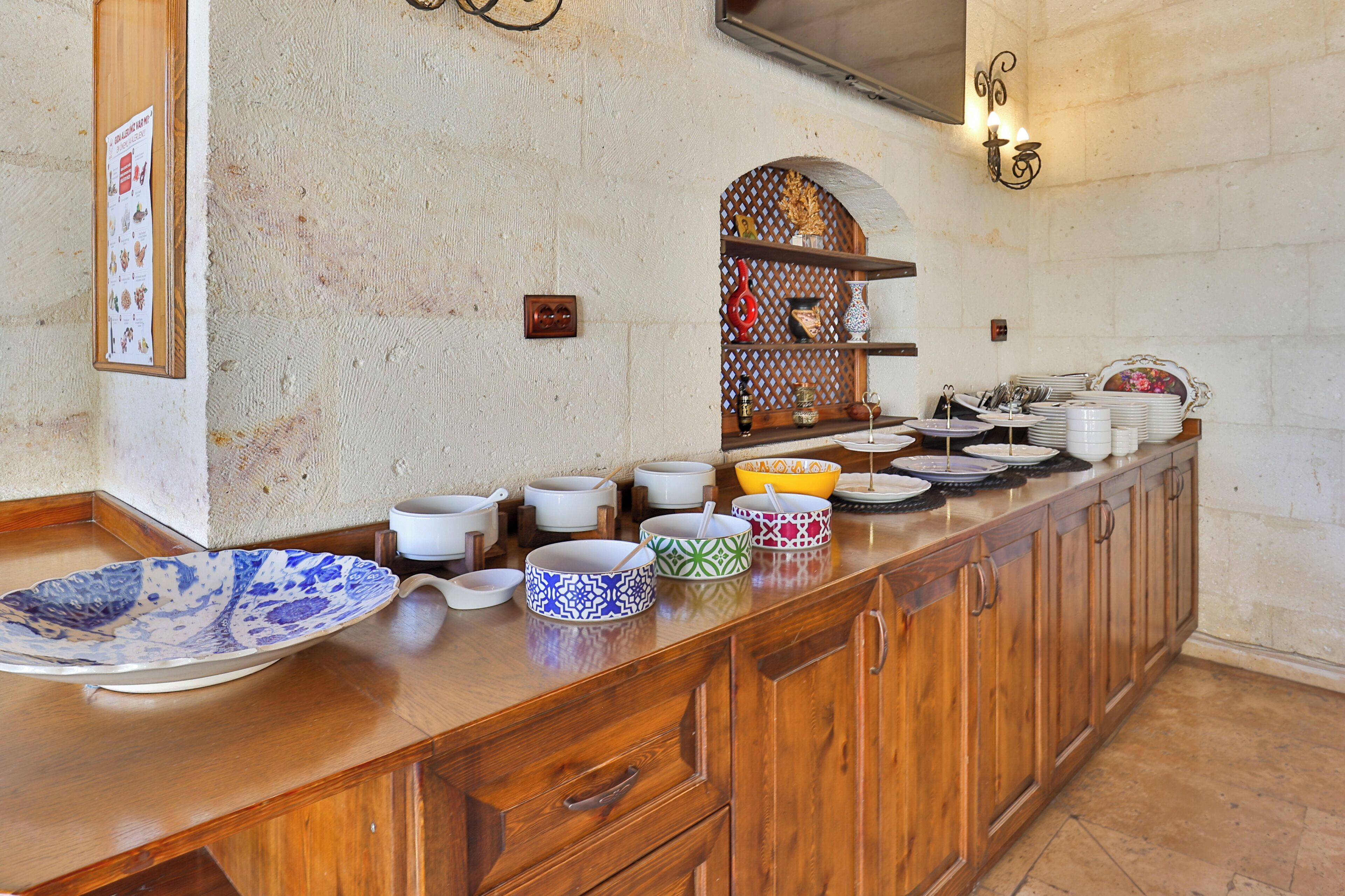 A buffet setup with various bowls and plates, wooden cabinets, and a decorative wall.
