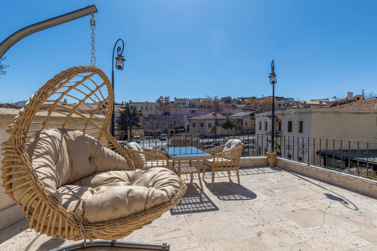 Terraço no telhado com mobiliário de vime, uma mesa e cadeiras.