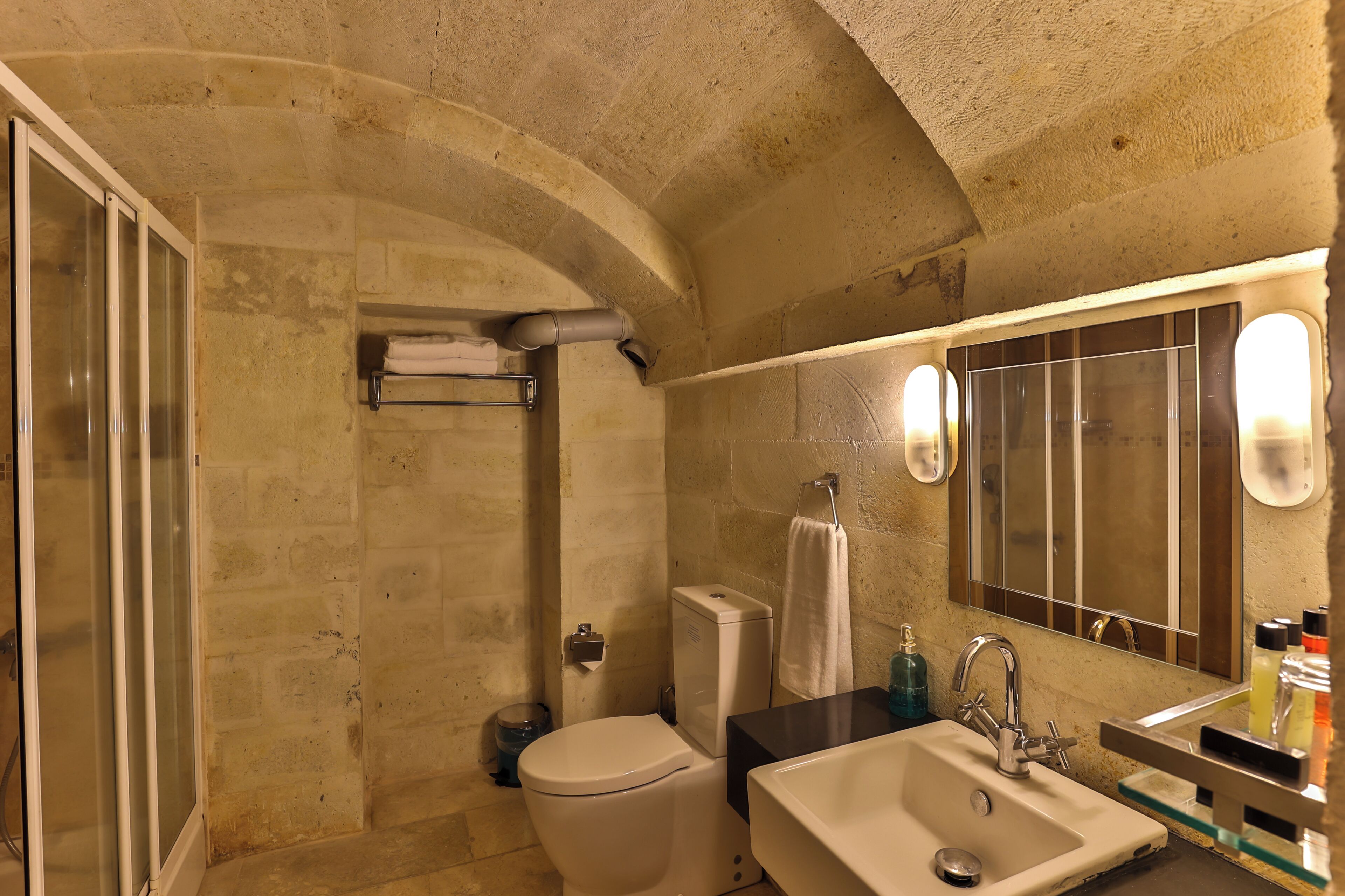 A bathroom with a shower, toilet, sink, and a large mirror.