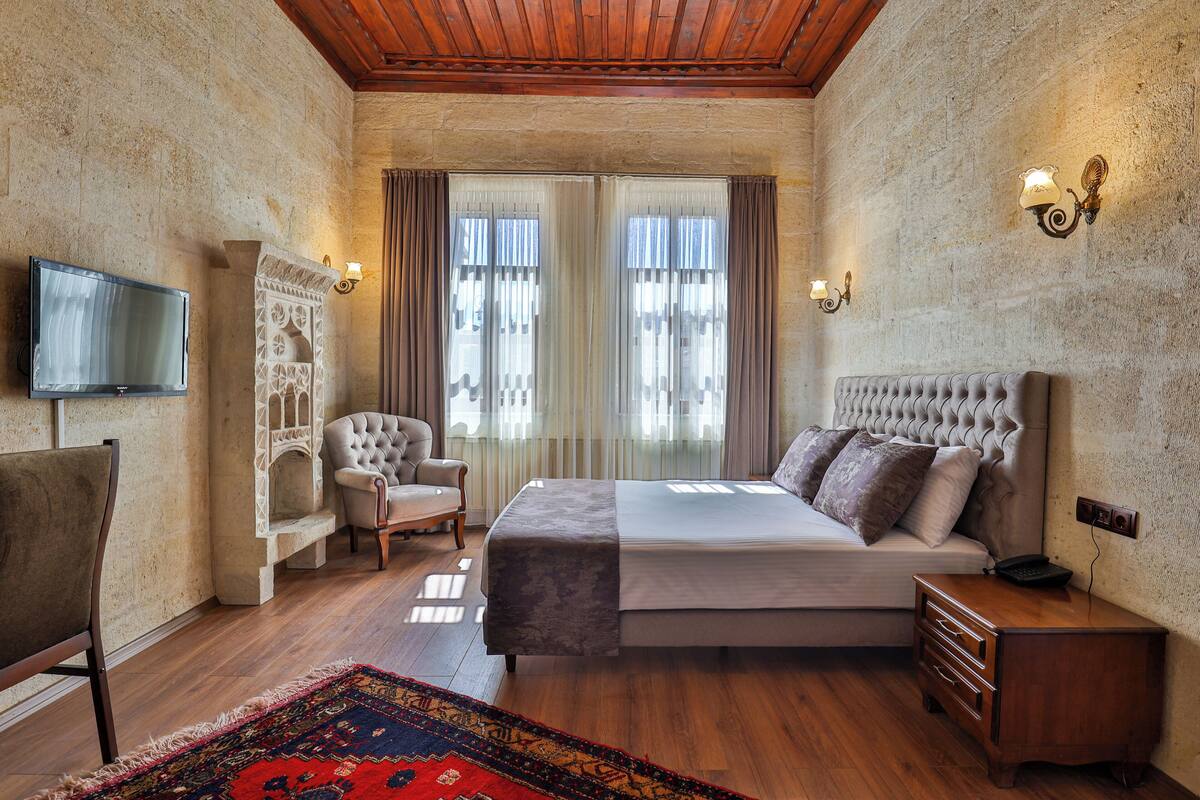 Quarto com cama grande, uma cadeira, televisão e mesa de cabeceira.