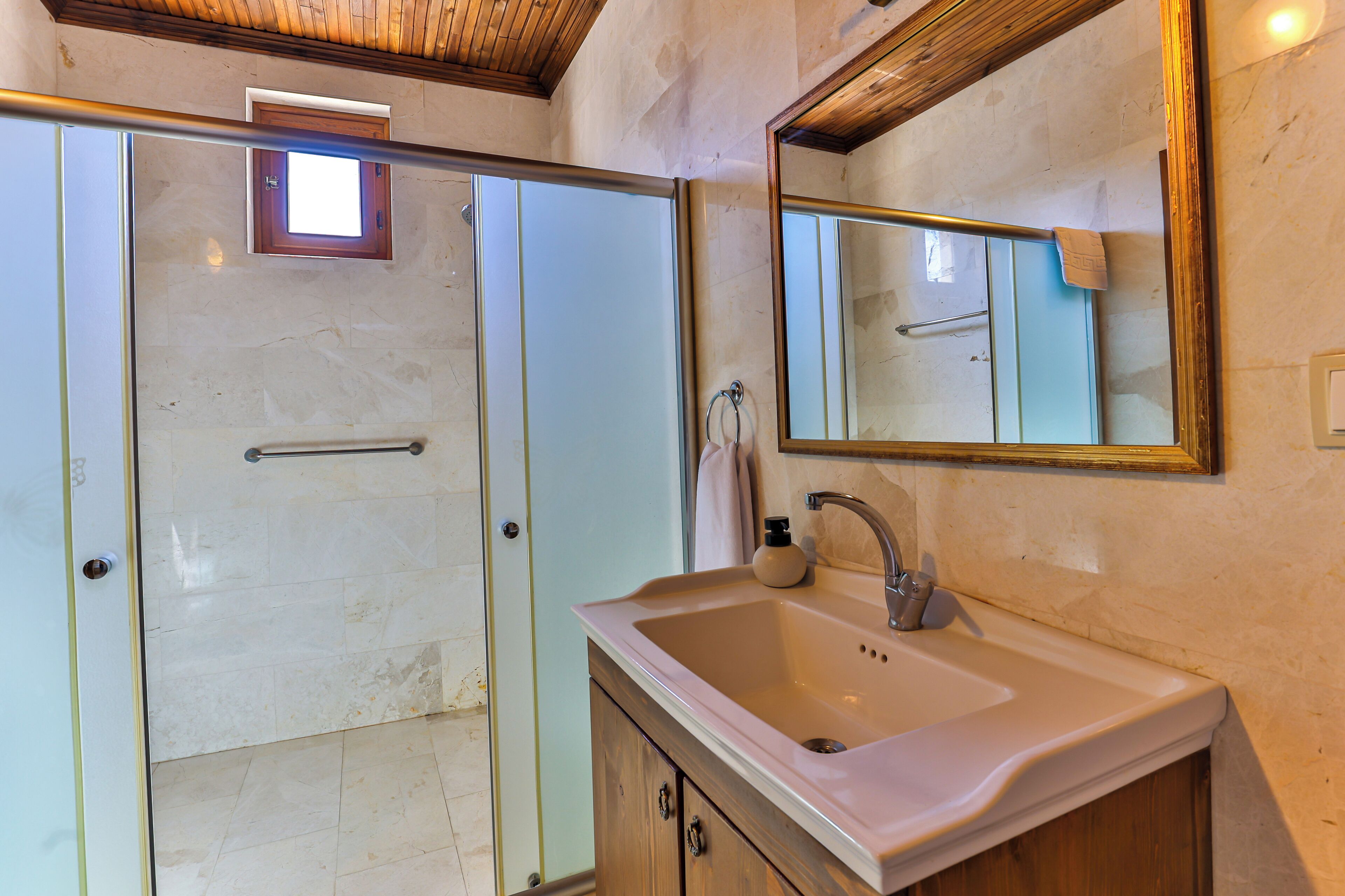 Un baño con mampara de vidrio, lavamanos y espejo.