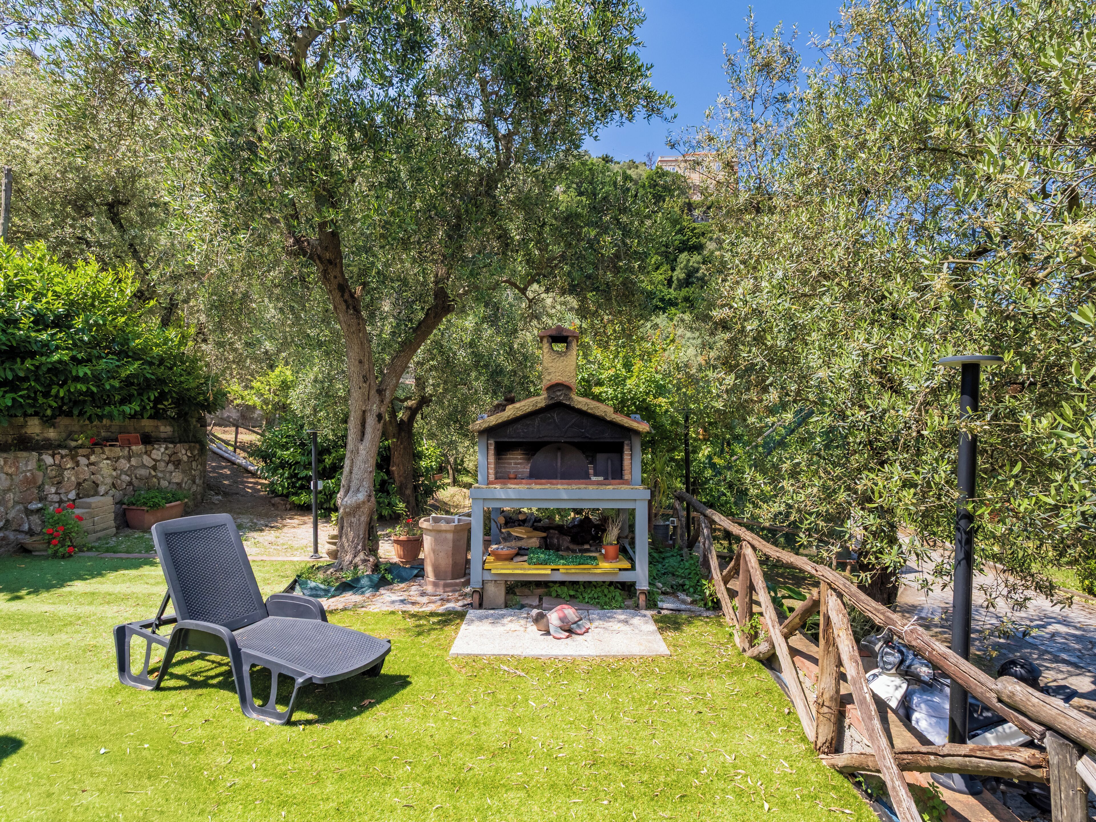 Ein Garten mit Grill, Stuhl und einer Steinmauer.