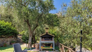 Un cortile con un barbecue, una sedia e un muro in pietra.