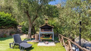 Ein Garten mit Grill, Stuhl und einer Steinmauer.
