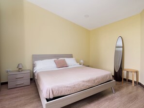 Een slaapkamer met een bed, nachtkastjes, een spiegel en een houten vloer.