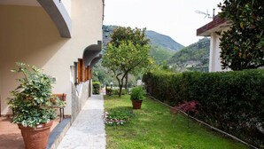 A pathway leading to a building with a stone floor, potted plants, and a view of a mountain. - 🌺Villa dei Fiori – Elegance, Nature & Serenity on the Sorrento Coast (Vico Equense)