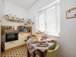 A compact kitchen with a dining area, equipped with a stove, microwave, and oven.