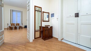 Un pasillo con piso de madera, un comedor con mesa y sillas, un espejo y un armario.