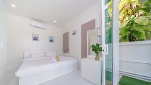 A modern bedroom with a large bed, a bedside table, a mirror, and a view of a green garden through a glass door. - Beachfront 2BR Pool Villa DelMar Kamala (Kamala)