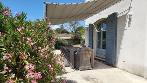 A patio area with a table and chairs, a pergola providing shade, and a building with a blue door. - Spacious 4 bedroom mas with AC, WiFi, wonderful view in a nice and quite place (Lioux)