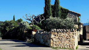 A stone building with a stone wall and a tiled roof, surrounded by trees and greenery. - Spacious 4 bedroom mas with AC, WiFi, wonderful view in a nice and quite place (Lioux)