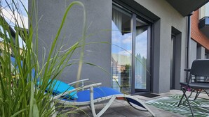 A modern outdoor seating area with a blue lounge chair, a black chair, and a patterned rug. - Apartament Loft 9 - 365PAM (Ustronie Morskie)