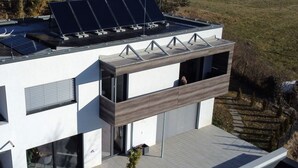 Ein modernes, zweistöckiges Gebäude mit Flachdach, großen Fenstern und einem Balkon.