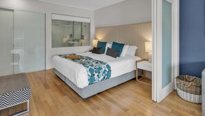 A modern bedroom with a large bed, bedside tables, a mirror, and a view of the bathroom. - The Sand Resort Kingscliff - One Bed Pool View (3208) (Tweed)