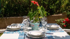 A table set outdoors with plates, glasses, and a potted plant.