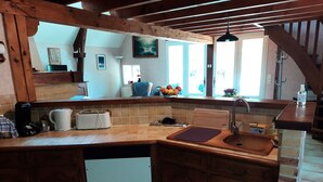 A kitchen with wooden cabinets, a built-in dishwasher, a sink, and a countertop with various appliances. - Gite LA GRANGE, in a quiet location close to Rocamadour, Padirac... (Bio)