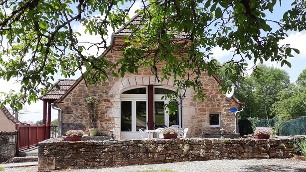 A stone building with a covered patio, outdoor seating, and a gravel driveway. - Gite LA GRANGE, in a quiet location close to Rocamadour, Padirac... (Bio)