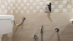 A bathroom with a toilet, a shower, and a sink. - Hotel Nithyanand (Mumbai)