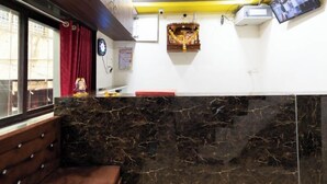 A room with a marble counter, a clock, a calendar, and a small shrine on the wall. - Hotel Nithyanand (Mumbai)