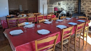 En restaurang med röda dukar och trästolar, stenmurar och en öppen spis.
