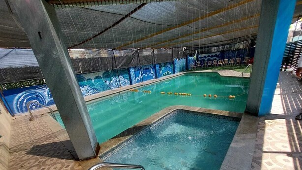 An indoor swimming pool with a tiled floor, a diving board, and a mural on the wall. - Yogi Golden Resort (Mysore)
