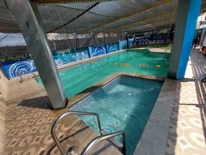 Una piscina interior con suelo de baldosas, un trampolín y un mural en la pared.