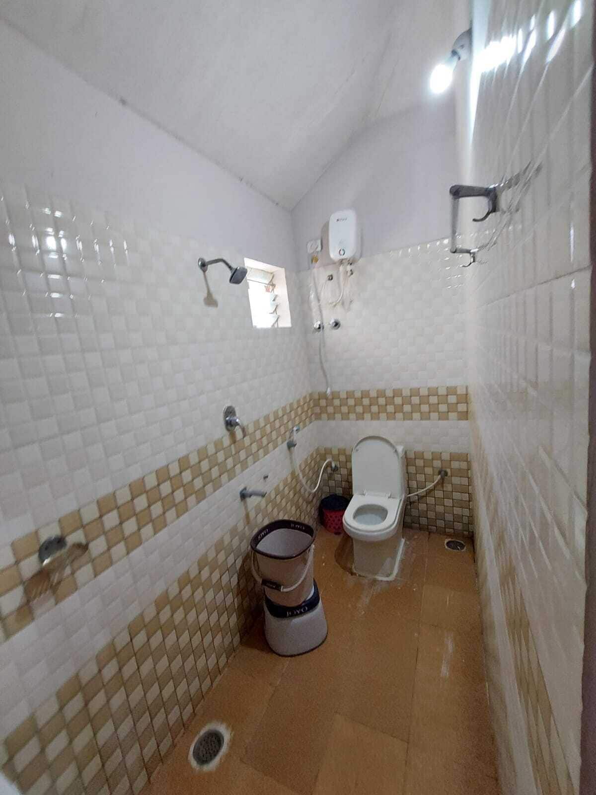Un baño pequeño con paredes de azulejos blancos, un inodoro, una ducha y un lavabo.