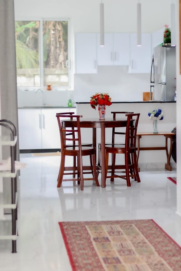 A modern kitchen with white cabinets, a dining table with chairs, and a vase with flowers on the table.