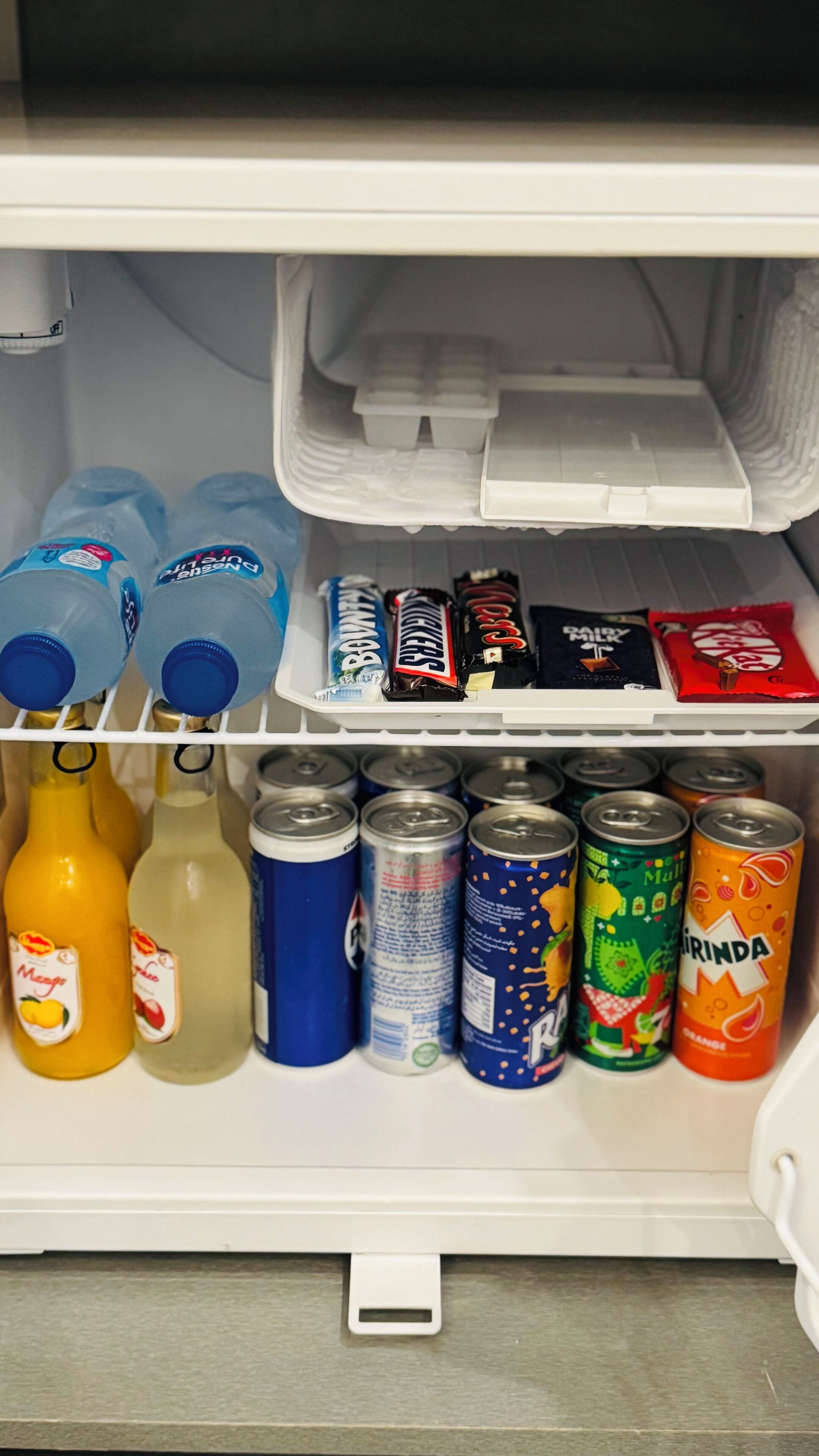 Un refrigerador con diversas bebidas y aperitivos.