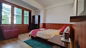 A hotel room with a bed, a desk, a chair, a window, and a wardrobe. - Hotel Ree Ghang  (Gangtok)
