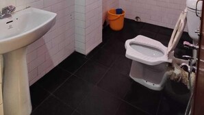 A bathroom with pink walls, a white sink, a toilet, and a shower area.