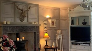 A room with a fireplace, a television, and a decorative deer head.