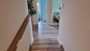 A hallway with wooden flooring and white walls.