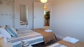 A hotel room with a bed, a hanging coat rack, a mirror, and a door leading to a bathroom.